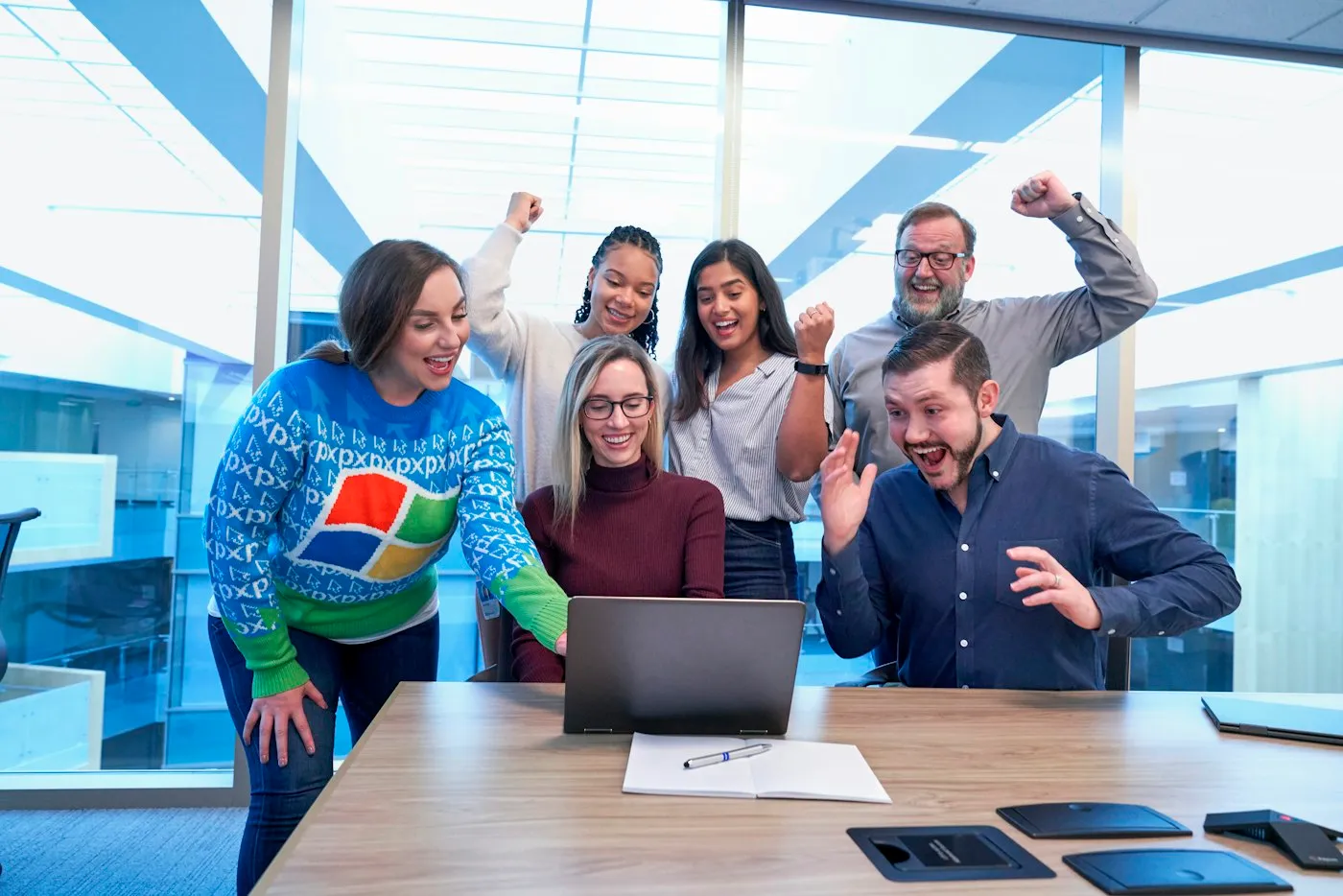 Team members gathered around a laptop, smiling