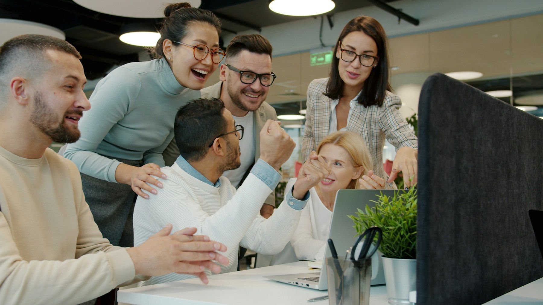 Team celebrating a success together at an office desk